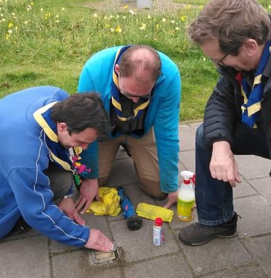 Scouts poetsen aan de Gasthuispoort de Stolperstein voor Eduard de Leeuw