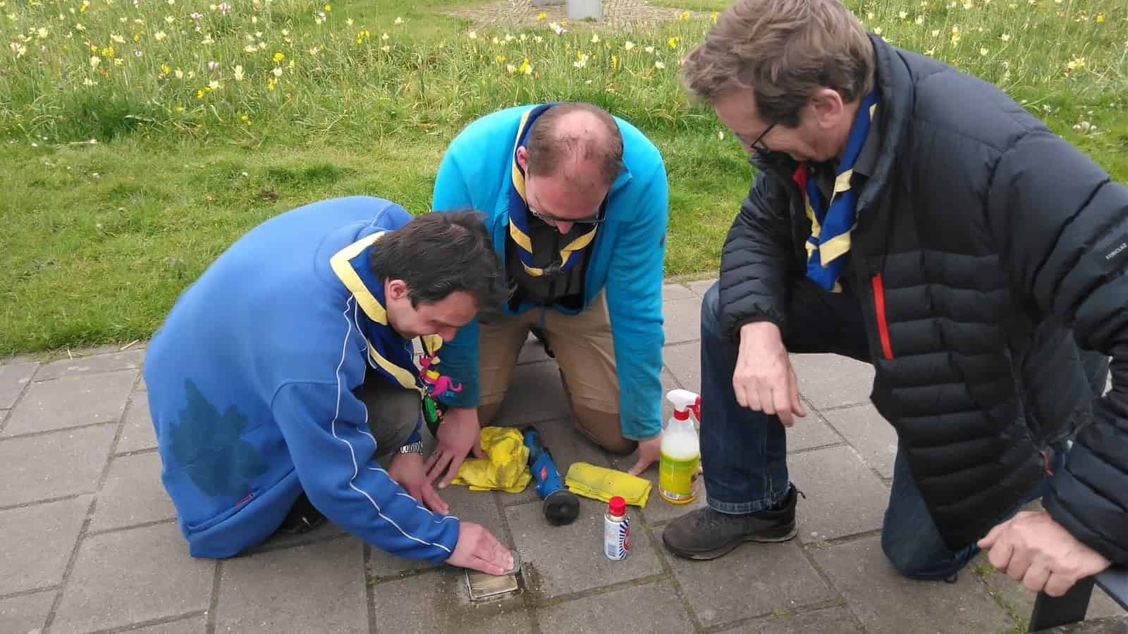 Scouts poetsen aan de Gasthuispoort de Stolperstein voor Eduard de Leeuw