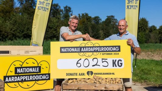 20240907_Aardappelrooidagen_001_ Dick Hylkema, directeur van de Nederlandse Aardappel Organisatie, overhandigt de cheque van 6050 kilo aardappelen aan Kees Bos van de Voedselbank bij deelnemende teler Lodders Landbouw in Dronten.