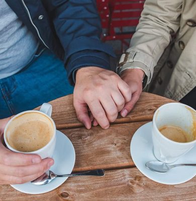 couple-holding-hands-while-drinking-latte-outdoors-cafe