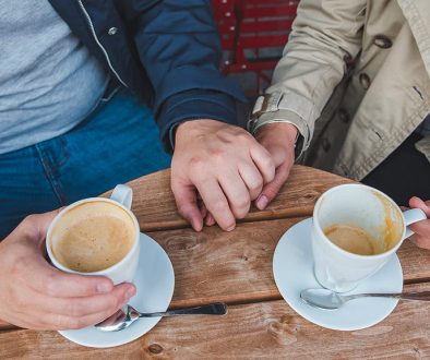 couple-holding-hands-while-drinking-latte-outdoors-cafe