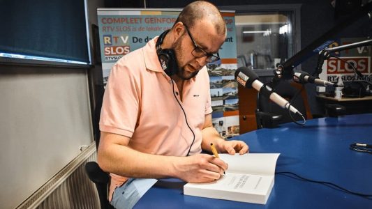 Tim de vries zet handtekening in zijn boek' Vive le Tour, Vive les Femmes'