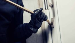 burglar using crowbar to break a home door at night