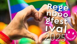 Kleurrijke handen vormen een hart tijdens het LGBT+ Pride Festival 2025 met regenboogvlag in de achtergrond.