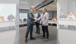 Uitreiking van een bloemenboeket tijdens een formele bijeenkomst bij RTV SLOS.