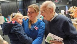 Vriendelijke jonge meid met ouder en grootouder die samen lachen, in een gezellige indoor evenement setting met kleurrijke decoraties, verbondenheid en familiewaarden, gericht op gemeenschap en cultuur, voor optimale SEO.