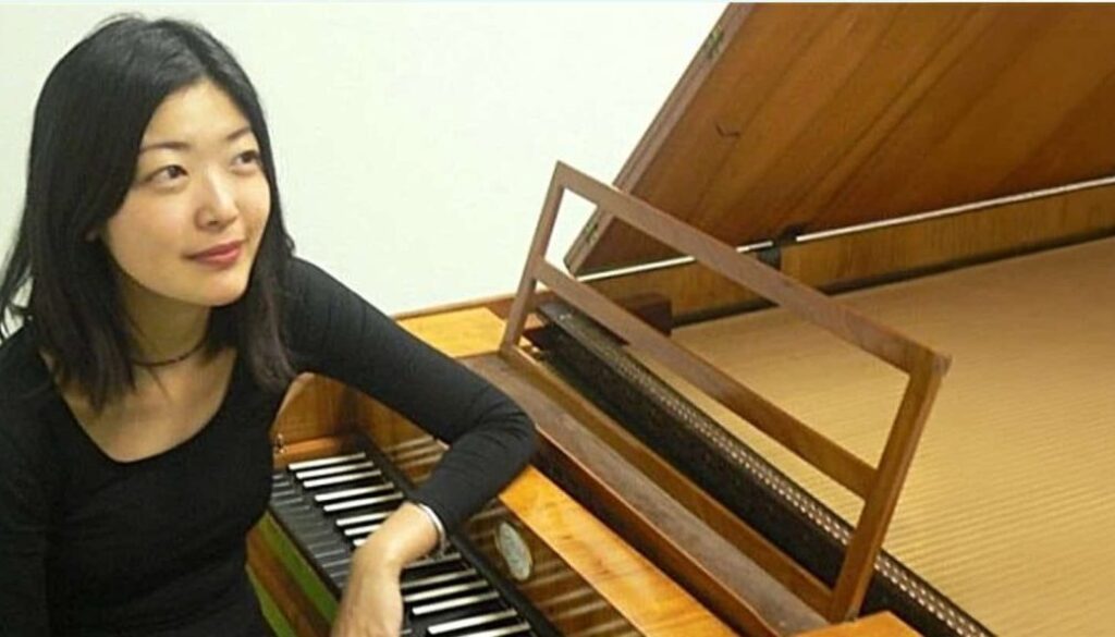 Mooie jonge vrouw die piano speelt op een houten klavecimbel in een sfeervolle muzikale setting.