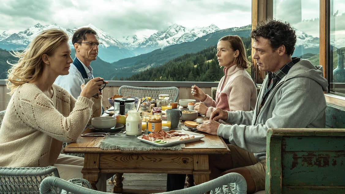 Gezinsontbijt met uitzicht op bergen, RTV SLOS, ontspannen gezichtsuitdrukkingen, ontbijttafel met brood, fruit en koffie, familie geniet van ochtendedrukte in bergachtig landschap, gezellig en rustgevend uitzicht, vakantie sfeer, outdoor ontbijt in Oostenrijk, zonnige ochtend met bergen, familie op terras, jongeren en ouderen samen ontbijten.