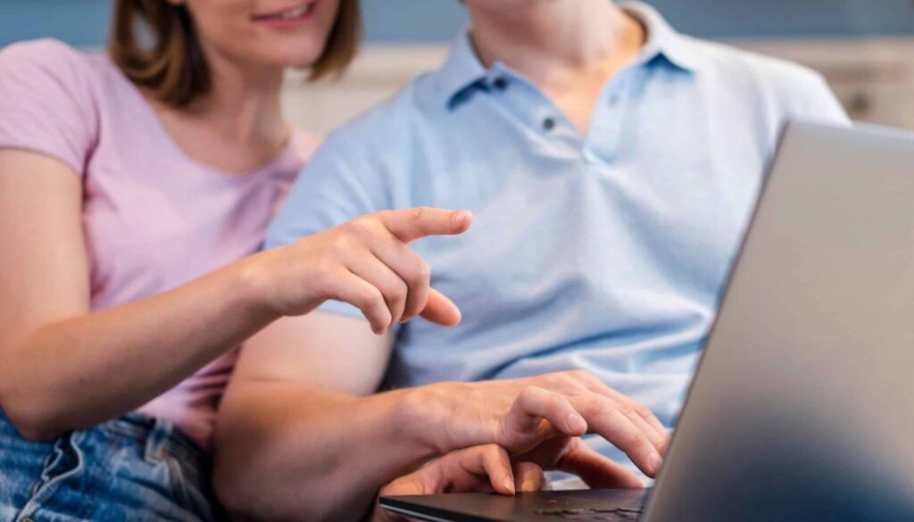 Klantenservice medewerker en klant werken samen met laptop, informele werksituatie, moderne kantoorsetting, technologiegebruik, focus op digitale communicatie, professionele samenwerking, teamwerk, klantgerichte service, online ondersteuning.