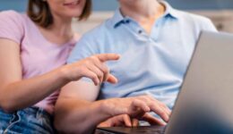 Klantenservice medewerker en klant werken samen met laptop, informele werksituatie, moderne kantoorsetting, technologiegebruik, focus op digitale communicatie, professionele samenwerking, teamwerk, klantgerichte service, online ondersteuning.