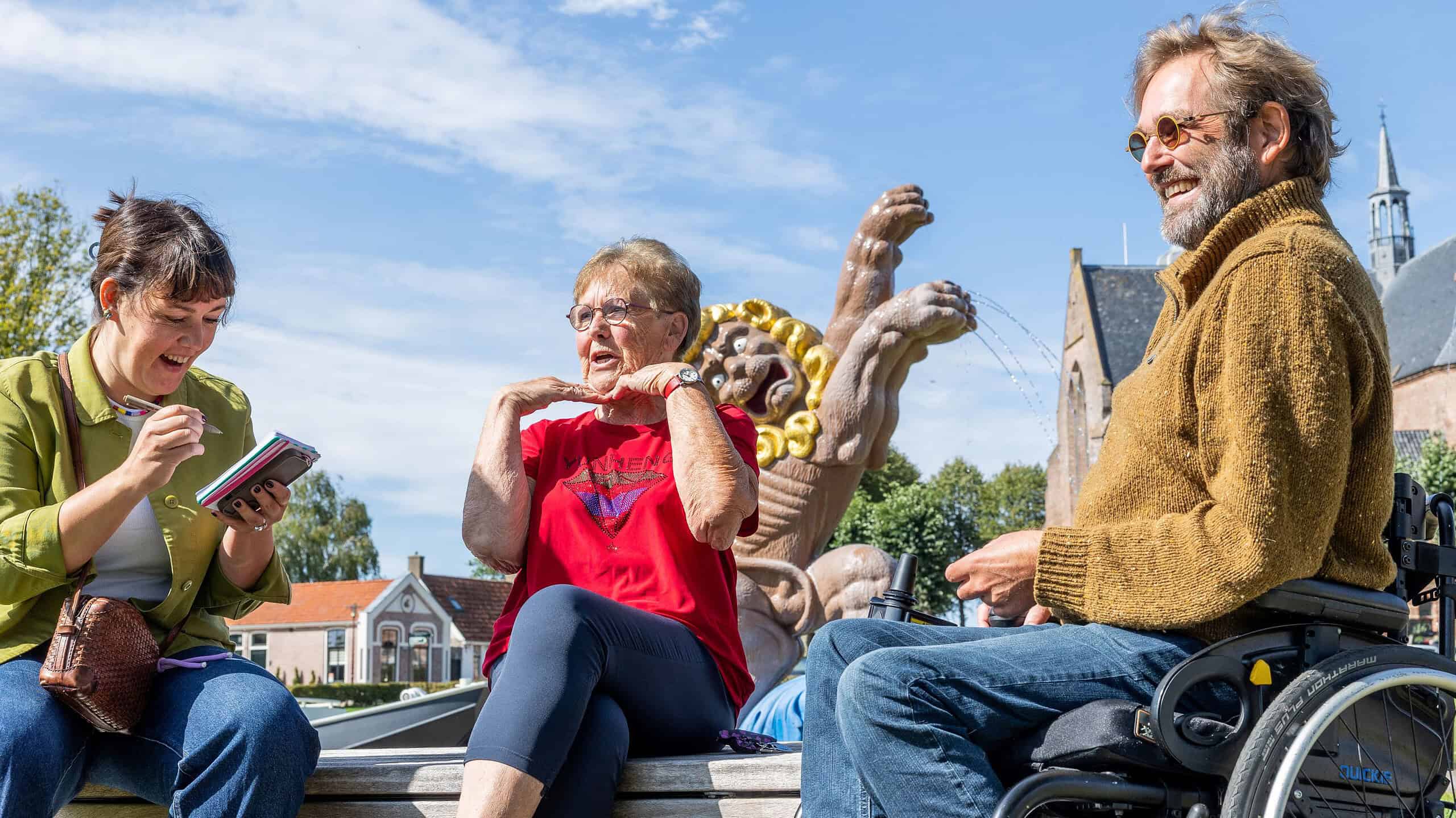 Vrolijke mensen in gesprek op een plein met beelden en een kerk op de achtergrond, glimlachend en genietend van een zonnige dag, benadrukt inclusieve gemeenschap en maatschappelijke betrokkenheid.