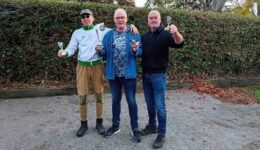 Laten zien van drie mannen die na een sportwedstrijd of competitie trots hun prijzen en bekers vasthouden, met een groen kleurrijke achtergrond.
