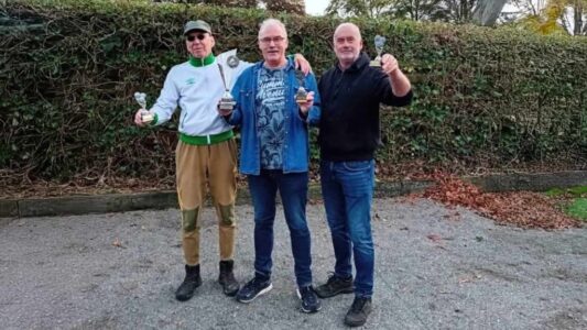 Laten zien van drie mannen die na een sportwedstrijd of competitie trots hun prijzen en bekers vasthouden, met een groen kleurrijke achtergrond.