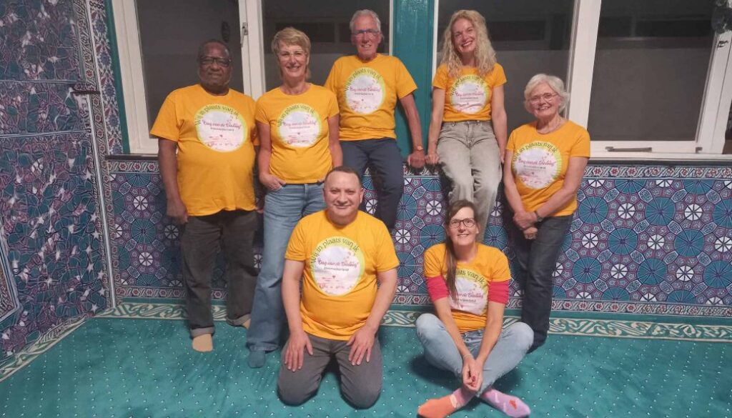 Samenwerkingsteam van RTV SLOS in kleurrijke setting tijdens community evenement.