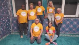 Samenwerkingsteam van RTV SLOS in kleurrijke setting tijdens community evenement.