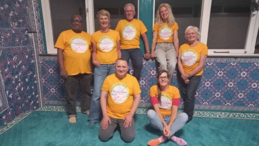 Samenwerkingsteam van RTV SLOS in kleurrijke setting tijdens community evenement.