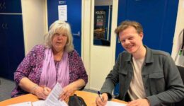 Aukje Oppersma (secretaris Omroep Odrie, namens de samenwerkende lokale omroepen) en Joey Teekamp tekenen de opdrachtovereenkomst. Foto: Streekomroep De Werven
