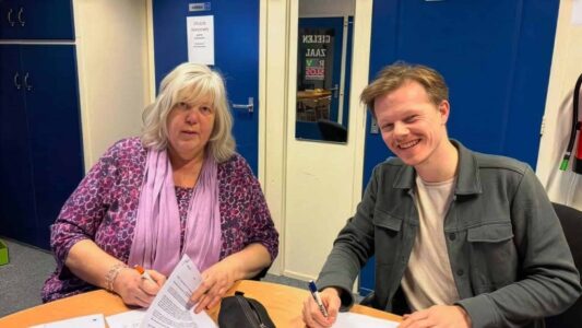 Aukje Oppersma (secretaris Omroep Odrie, namens de samenwerkende lokale omroepen) en Joey Teekamp tekenen de opdrachtovereenkomst. Foto: Streekomroep De Werven