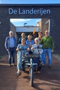 Bestuursleden Gerard Meijerink, Yme van der Valk, Lydia Schot, Marieke Pit, Marcel de Jong, op de duofiets vlnr: Alie Jongschaap en Loes Frissen (foto aangeleverd)