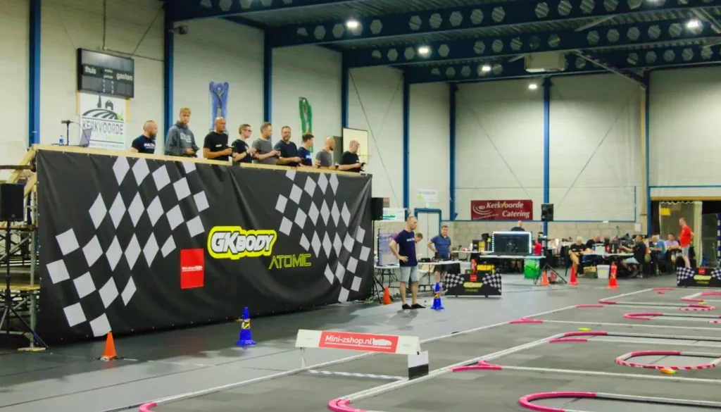 Zo ziet Sporthal De Schakel eruit als er geracet wordt: de baan, de verhoogde rijdersstand en de pits. Dit is GKbody International in augustus 2026 (foto Mini-Zshop)