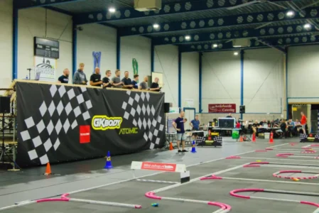 Zo ziet Sporthal De Schakel eruit als er geracet wordt: de baan, de verhoogde rijdersstand en de pits. Dit is GKbody International in augustus 2026 (foto Mini-Zshop)